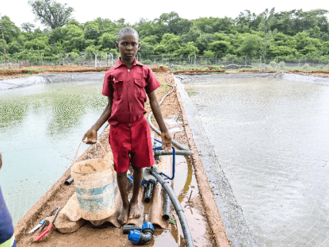 Gainmore, a Grade 7 learner, proudly shows off the fish pond