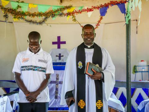 Rev, Jackson leading a church service, next to him is a World Vision Volunteer