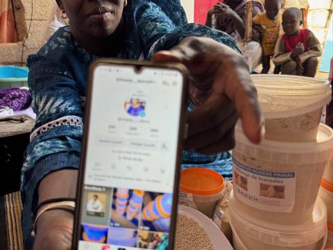 Aïssata Diarra, president of the Hodere Pinnal cooperative in Nouakchott, displays her TikTok account while surrounded by processed cereal products.