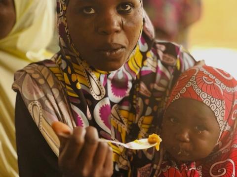Aichatou ici en train de nourrir sa fille sur le site du foyer de nutrition communautaire de son village.