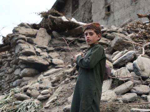 Child in Afghanistan stands in front of rubble following devastating earthquakes