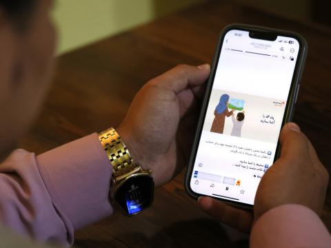 Over the shoulder view of a woman looking at cell phone screen.