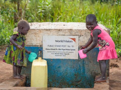 Two young girls enjoy clean water from the source near their home.