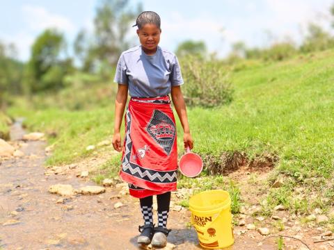 Sibonelo standing on a rock on the river she used to get water from before World Vision brougt water to her community. 