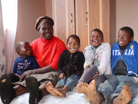 Linah Bhembe and her grandchildren sitting on a mattrass they received through World Vision's GIK Programme. 