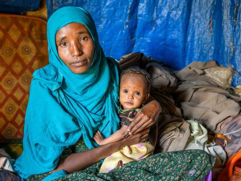 Nazifa holding her severely malnourished 8-month-old daughter Nafile.
