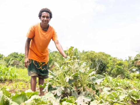 Siwakato Kena showcasing the vegetable crops thriving in her garden plots.