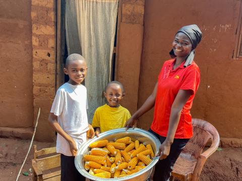 Catherine and two of her children proudly hold the ears of maize harvested from their field.
