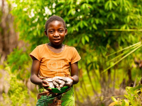 11 year old Lucy carrying fish from her fathers fish dam. Malawi