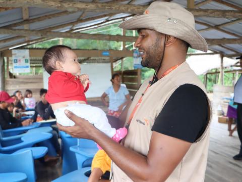 World Vision staff member holds a child