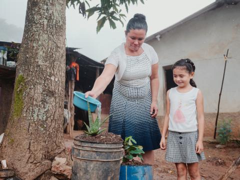 A woman and a young child water small plants outside their home in a rural Honduran village.