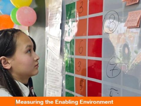 A young girl looks at a whiteboard with various colored papers and notes taped on. The title of the report is in the middle of the image.