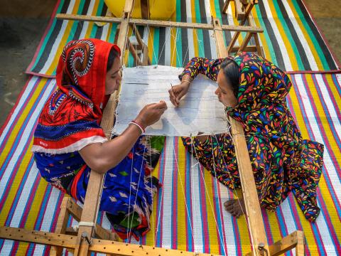 Two women in working together on a wooden embroidery frame as part of a World Vision Bangladesh economic empowerment project