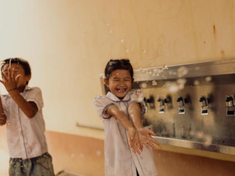 Two children laughing and splashing water