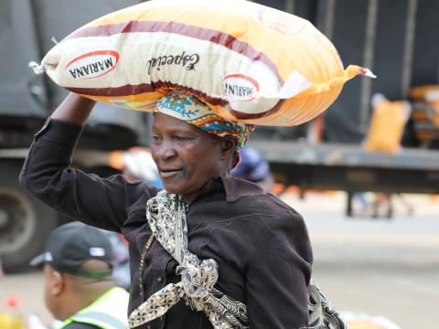 Sarafina carries a heavy sack of rice, a burden that for her represents relief and hope after the floods.