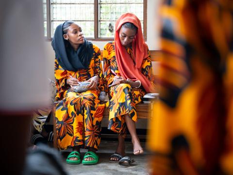Two girls sitting, listening to someone speak