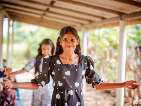 A girls smiles at the camera while holding out her arms