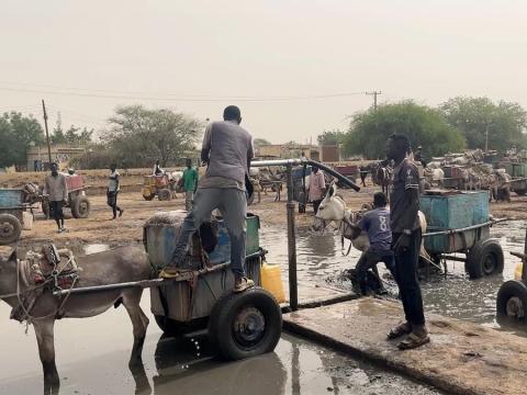 In Sudan's Darfur region, donkey carts are being loaded with large water tanks.