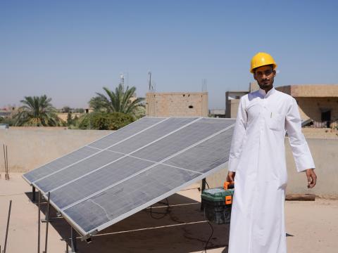 Ammar* standing next to a solar panel he built