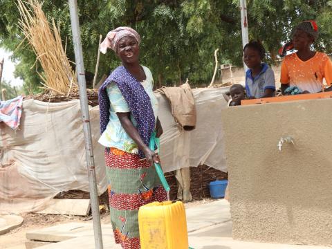 A mother draws water from a tap built by World Vision 