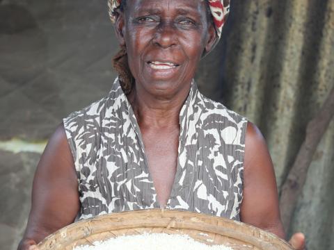 Salfina holds a sieve filled with rice.