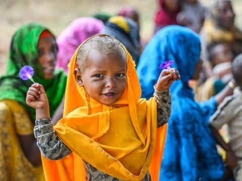 Girl holds morning glory flowers at a Nurturing Care Group meeting in Ethiopia, where mothers learn to feed nutritious meals to their children.