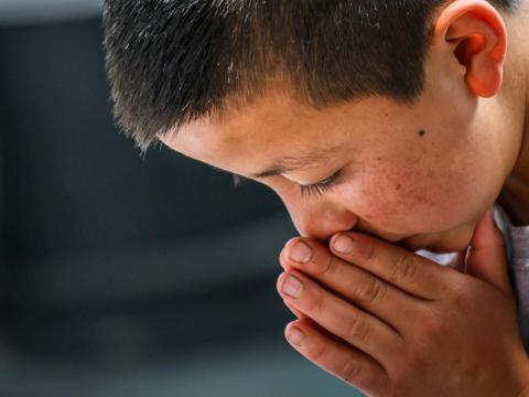 A sponsored child from Guatemala praying