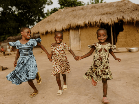 Little girls from Ghana, running holding hands
