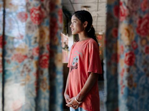 Win, a 12-year-old Rohingya refugee girl, stands inside her camp in Cox's Bazar, Bangladesh, smiling with quiet determination.