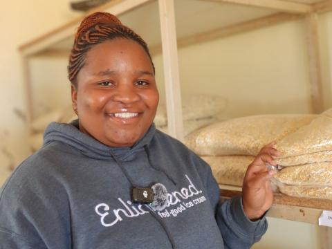 A woman standing next to animal feed inside a shop. 