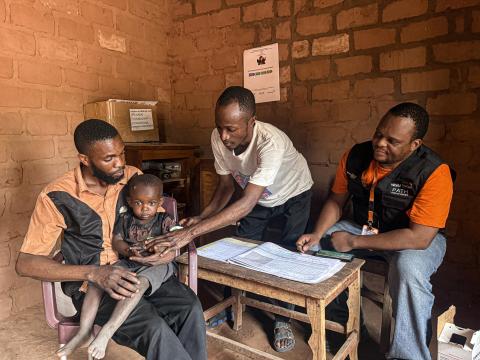 community health worker in a care site taking measures of a child