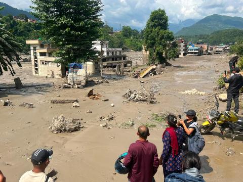 Families look at  houses and infrastructure submerged under flash-floods 