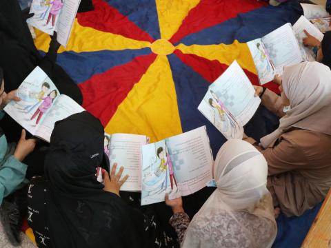 Children reading A Fig Tree and an Incomplete Picture at Dar Al-Karma publishing house. 