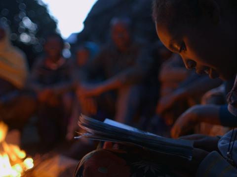 Tizta, 9, reads a story to her family outside their home in Ethiopia