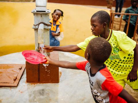 Children enjoying safe drinking water from a hand pump water well