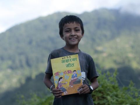 Child holds mother language book