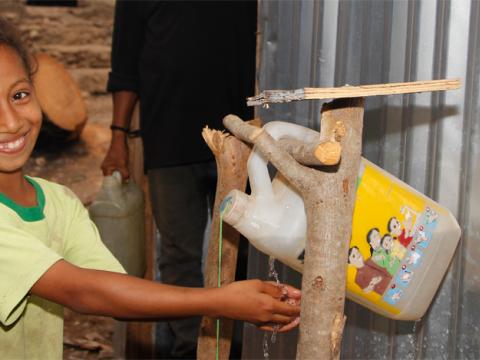 Nine-year-old Devia washes her hands with a tippy-tap at her home before meals and after going to the toilet. Photo: Jaime dos Reis/World Vision