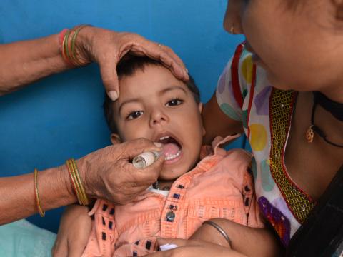 Yash, a sponsored child, getting his routine polio drops from a community health worker