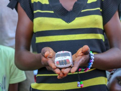 A girl holds the model car she's made at the Child Friendly Space Children at Child Friendly Spaces learn local handicrafts as a form of art therapy
