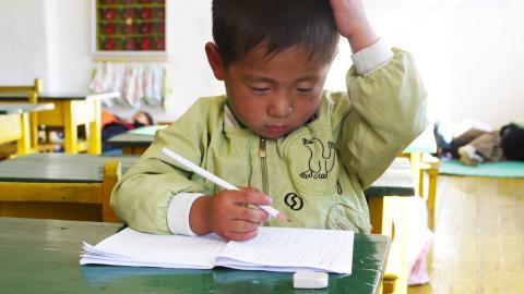 A young boy reads a book in school