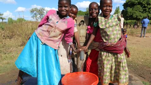 Children standing around a bucket of clean water