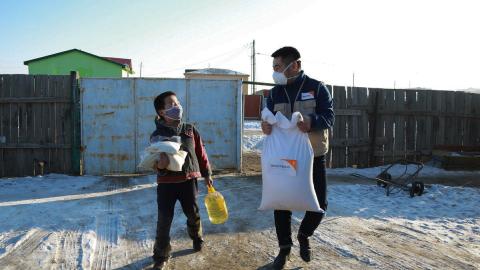 World Vision staff helping child with mask and food distribution during pandemic