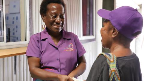 Paula Arnold, case finding officer from Anglicare, assists a peer educator receive her transportation and communication allowance.