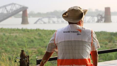 World Vision emergency response staff looking out over water towards a bridge in the distance.