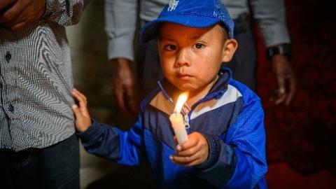 A little boy holding a candle.