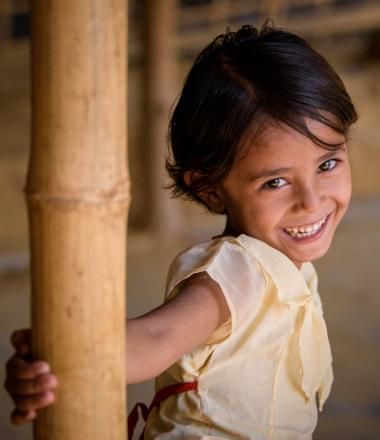 A girl smiles while holding a support beam in her home
