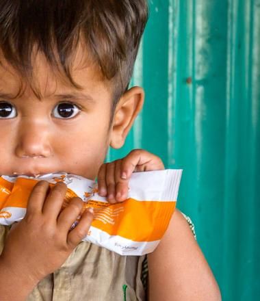 A boy eats food from a pouch in Rohyinga.