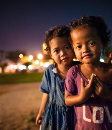 Two young Khmer children stand in the street