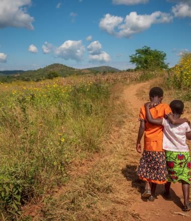 Two children walk down a road in Africa