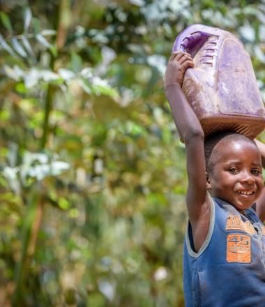 Rwandan girl carries water home